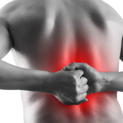 black and white image of man with fists clenched in front of his middle back, which is colored red to show pain