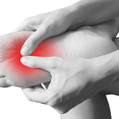 black and white image person pressing on the ball of their foot, which is colored red to show pain