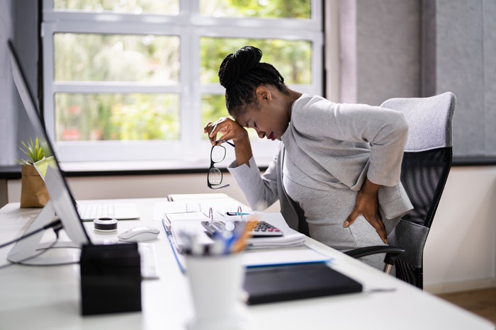 Woman at desk suffering from back pain